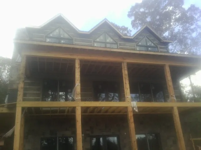 Dormers and porch framing on a large log home under construction — Roof Coating work by our crew in Strongstown