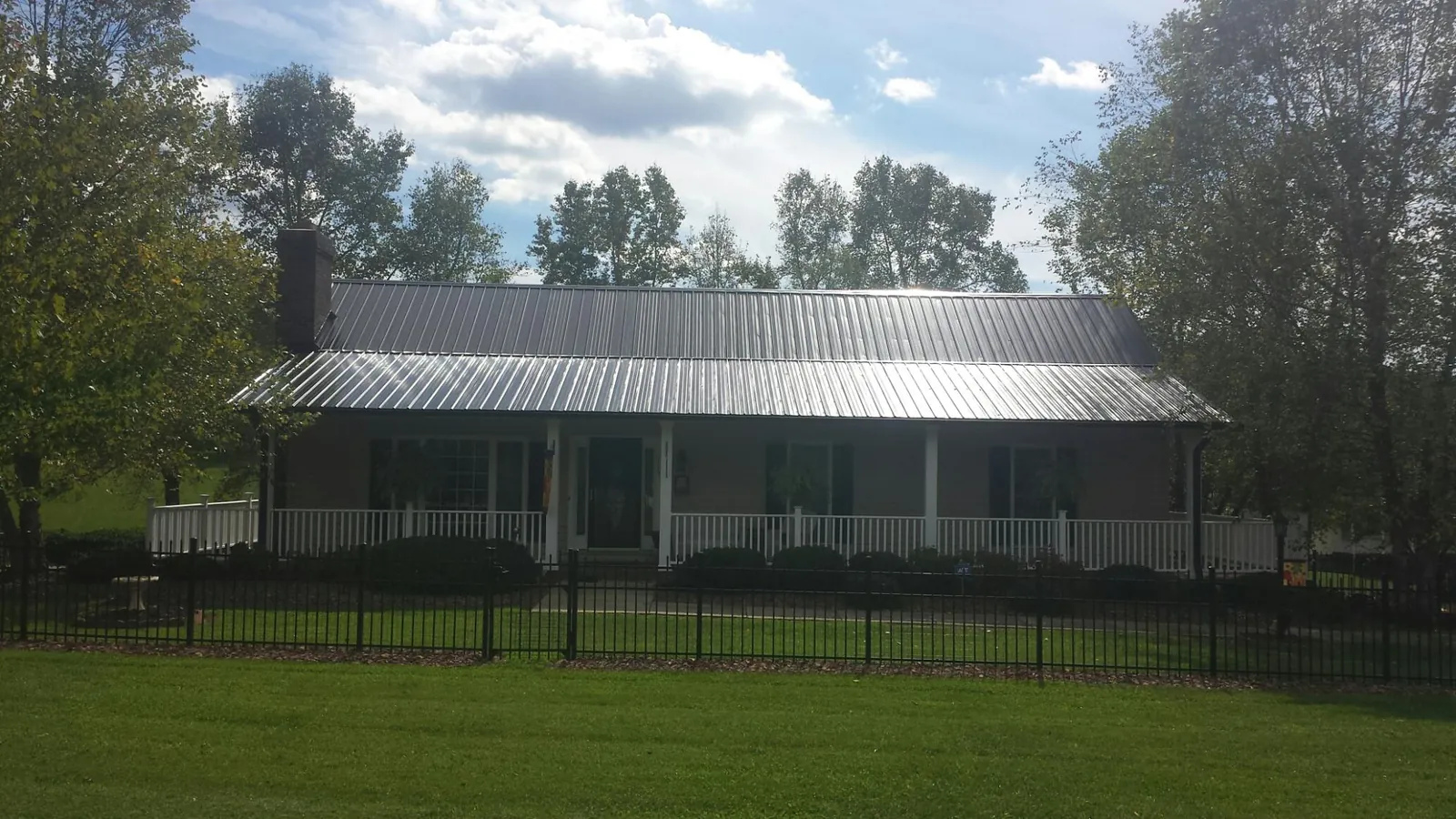 Gray metal roof on a brick ranch with a full width front porch — Gutter Guard Installation work by our crew in Strongstown