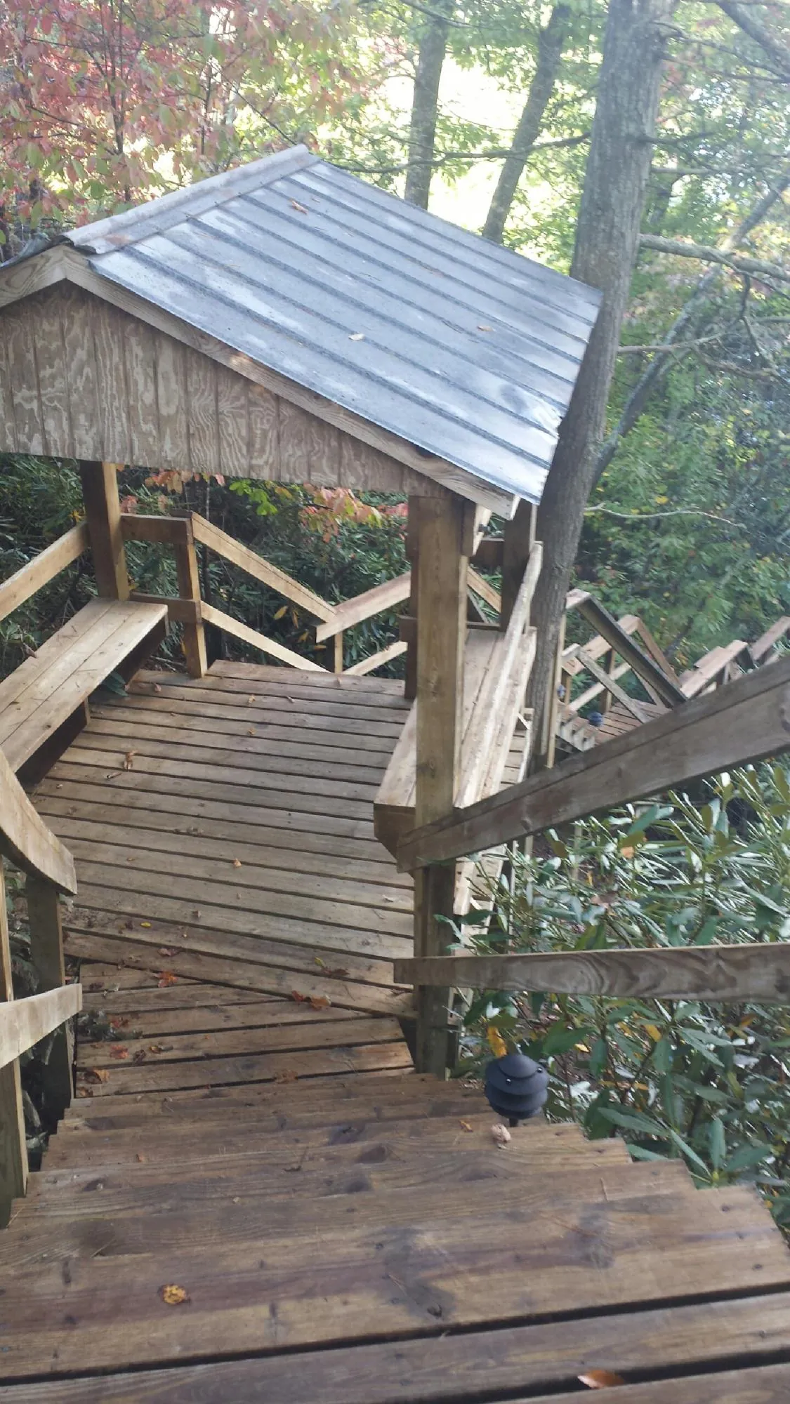 Metal roofed shelter over wooden steps on a wooded walkway — Skylight Repair & Installation work by our crew in Strongstown