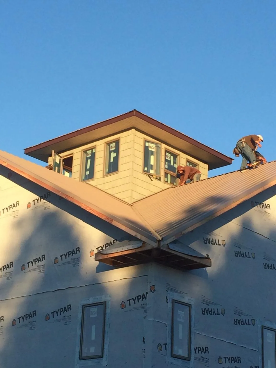 Roofers working around a rooftop cupola on a new metal roof at sunset — Roof Waterproofing in Strongstown by Roofing Brothers